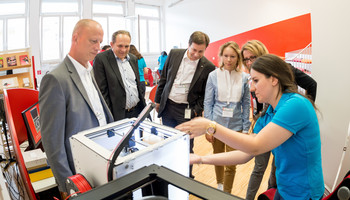 Regionale Bildungsstrategie | © MRN GmbH Menschen stehen beieinander und schauen auf einen technischen Apparat | © MRN GmbH