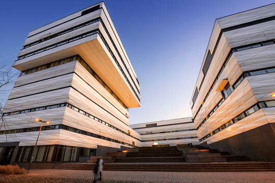 Zwei Gebäude, aufgenommen aus der Froschperspektive mit modern aussehender, strukturierter, weißer Fassade vor blauem Himmel | © MRN GmbH