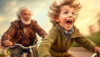 Opa fährt mit Junge lachend Fahrrad | © Adobe Stock / Victor
